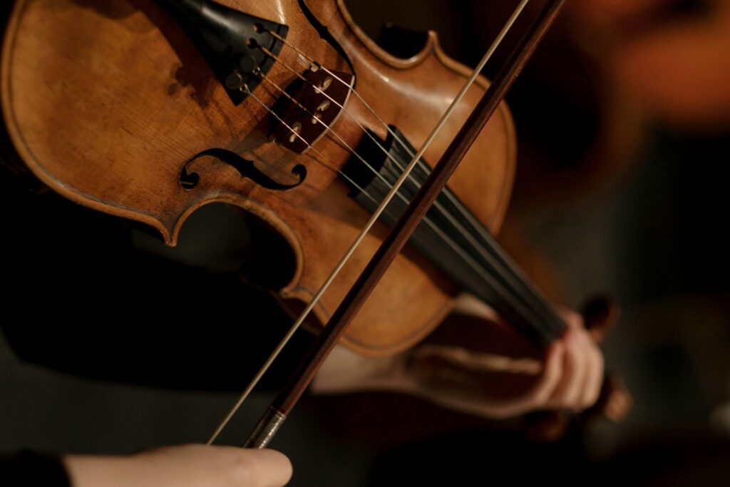 A Person Playing Violin while Holding a Violin Bow