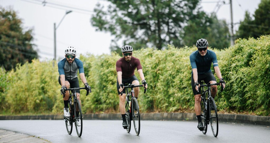 Unrecognizable bicyclists riding bikes on roadway in summer