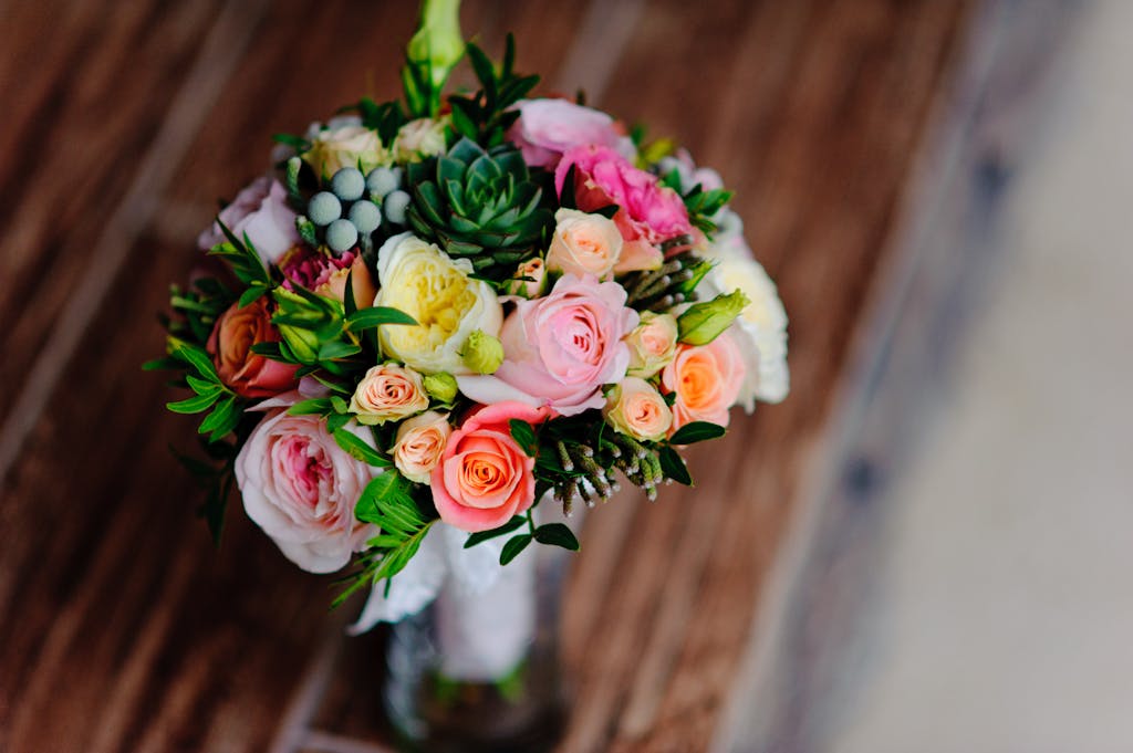 A top-view of a beautiful bouquet featuring roses, succulents, and greenery, perfect for weddings or celebrations.