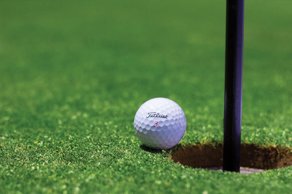 Close-up of a golf ball near a hole on a vibrant golf green, capturing the moment of near success.