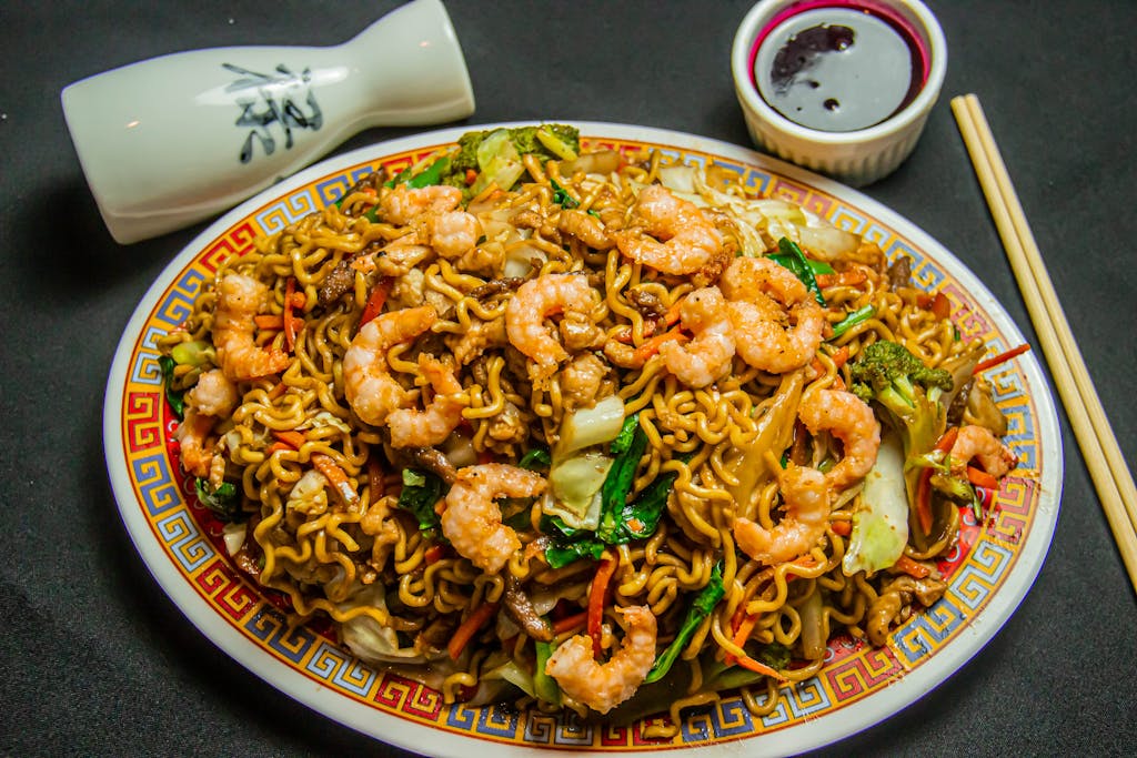 Delicious shrimp noodles with vegetables on a traditional plate, perfect for Asian cuisine lovers.