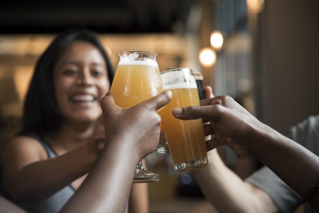 Friends enjoying drinks and toasting in a lively indoor bar setting.