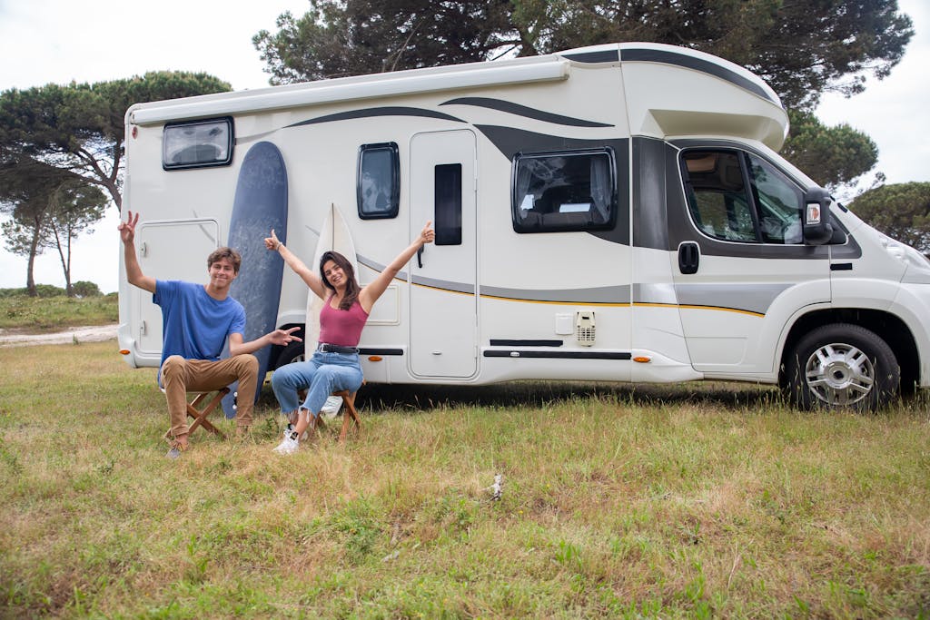 Happy couple relaxing by camper van in sunny campsite,