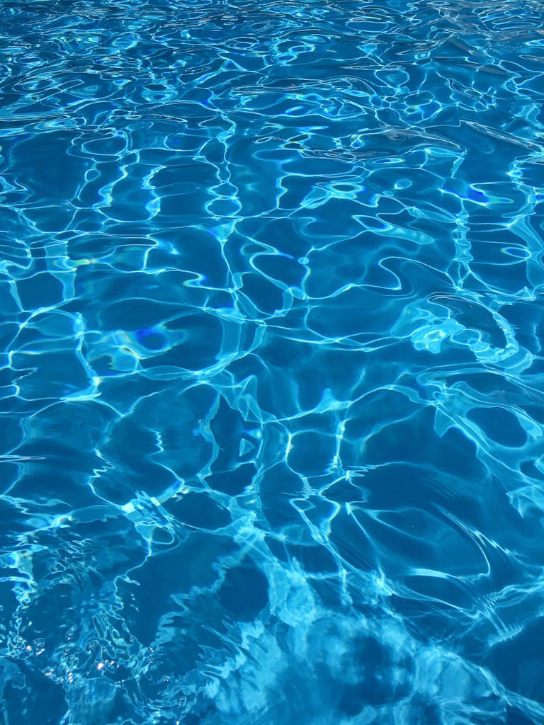 Vibrant blue swimming pool water with dynamic reflections, ideal for abstract backgrounds.